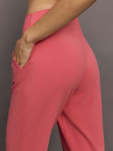 Model wears a buttery soft, high waisted, salmon pink colored pair of jogger sweatpants. 