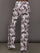 Model wears white track pants with burgundy toile print. 