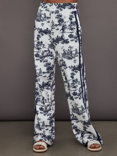 Model wears a pair of high waisted track pants in white with blue toile print and navy drawstring.