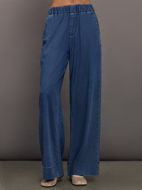 Model wears medium wash pants with an elastic waist and relaxed, wide-leg fit.