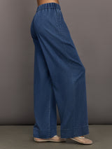 Model wears medium wash pants with an elastic waist and relaxed, wide-leg fit.