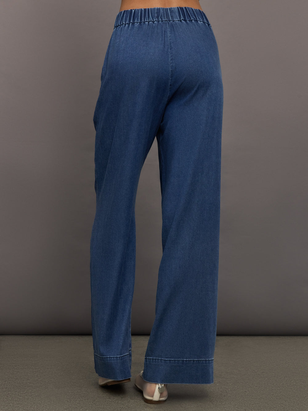 Model wears medium wash pants with an elastic waist and relaxed, wide-leg fit.