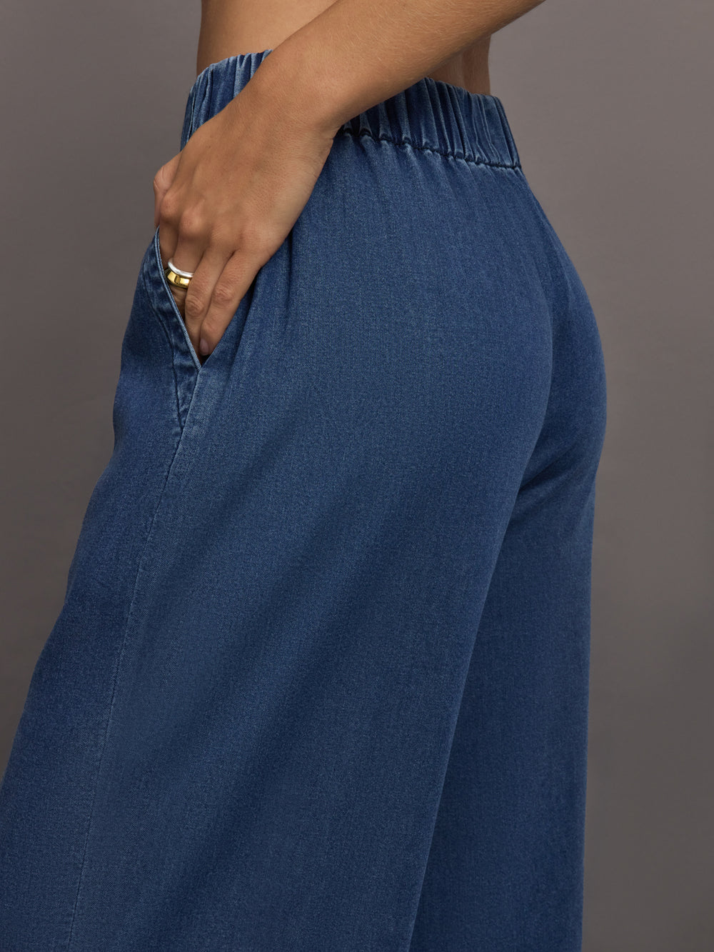 Model wears medium wash pants with an elastic waist and relaxed, wide-leg fit.