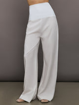 Model wears high-waisted, white wide-leg linen pants.