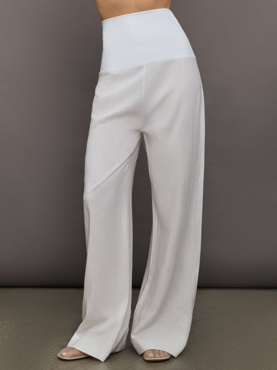 Model wears high-waisted, white wide-leg linen pants.