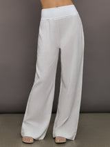 Model wears high-waisted, white wide-leg linen pants.