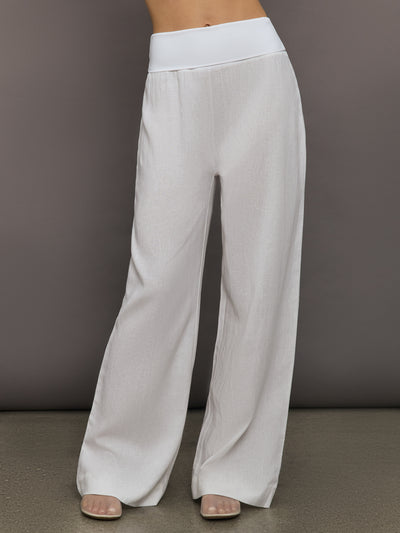 Model wears high-waisted, white wide-leg linen pants.