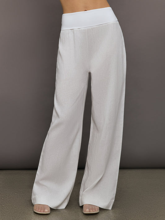 Model wears high-waisted, white wide-leg linen pants.