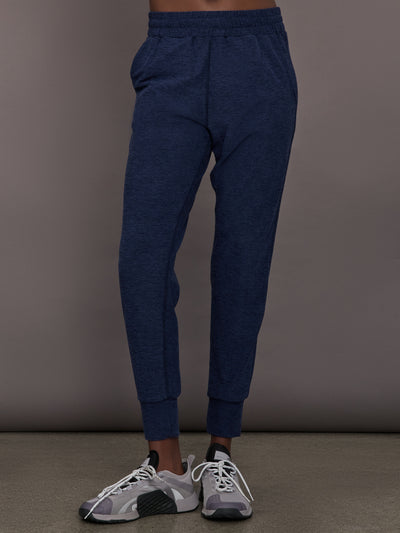 Model wears mid rise navy joggers with thick ankle band. 