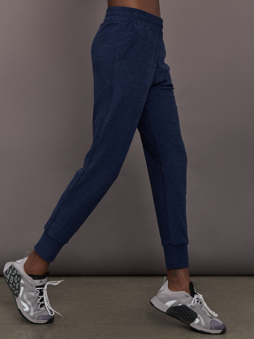 Model wears mid rise navy joggers with thick ankle band. 