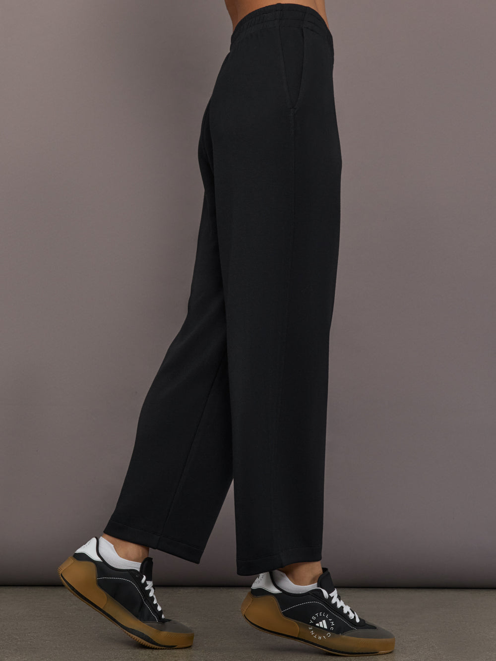Model is wearing Interlock barrel leg pant in black, side view.