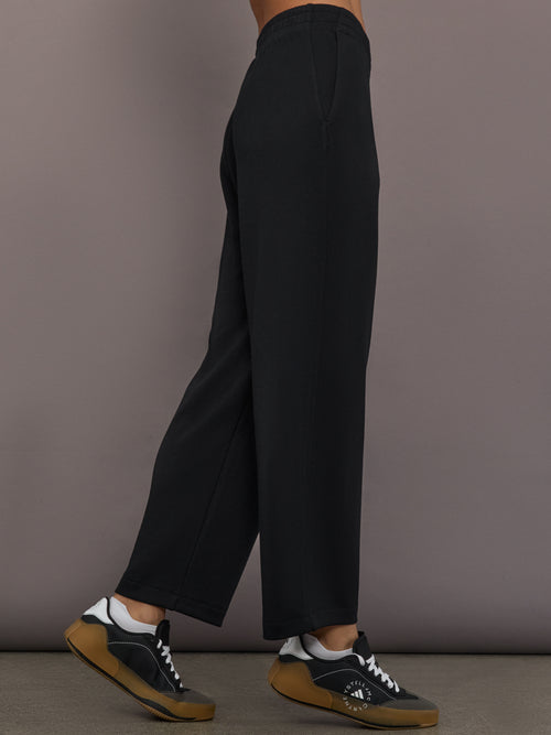 Model is wearing Interlock barrel leg pant in black, side view.