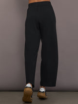 Model is wearing Interlock barrel leg pant in black, back view.