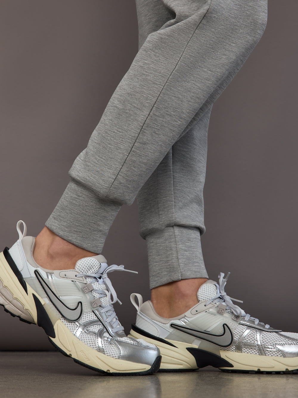 Close-up of heather grey Ultrasoft Cargo Bomber with tapered ankle cuff detail, styled with silver Nike sneakers.