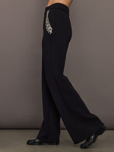 Side view of black embellished wide-leg pants showing jeweled pocket detail and flared silhouette.