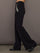 Side view of black embellished wide-leg pants showing jeweled pocket detail and flared silhouette.