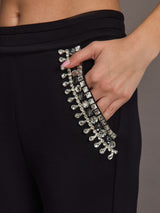 Close-up of jeweled embellishment on black wide-leg pants pocket.