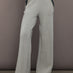 Model wearing grey wide-leg embellished pants with jeweled pocket trim, front view.