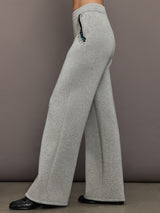 Side view of grey embellished wide-leg pants showing jeweled pocket detail and flared silhouette.