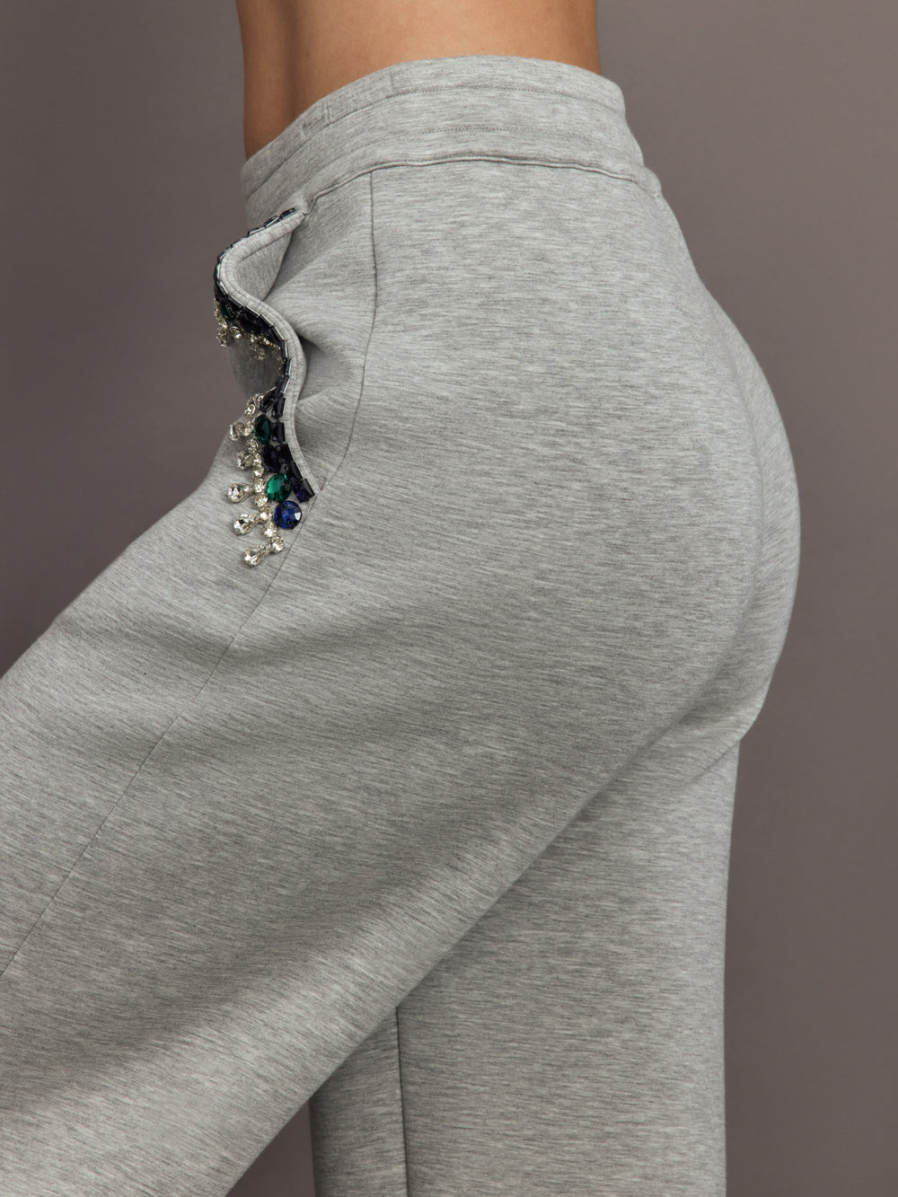 Close-up of grey wide-leg pants pocket featuring blue and green jewel embellishments.