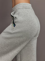 Close-up of grey wide-leg pants pocket featuring blue and green jewel embellishments.