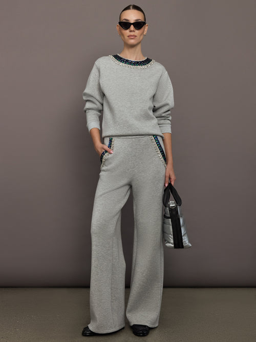 Full body view of grey jewel embellished sweatshirt styled with matching pants and sneakers.