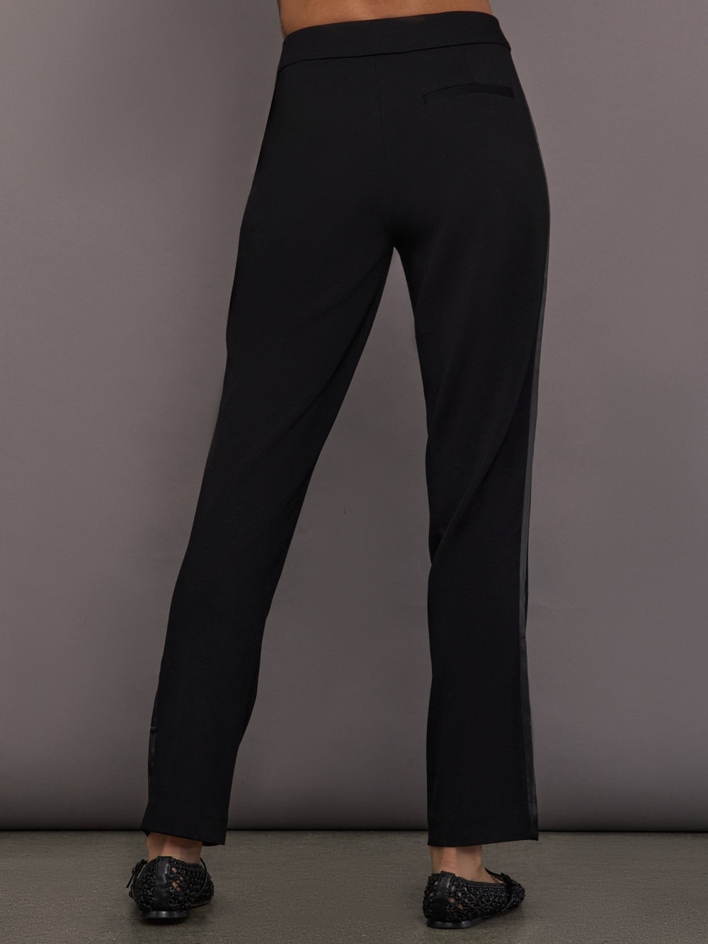 Model is wearing the scuba tuxedo pant in black, back view.