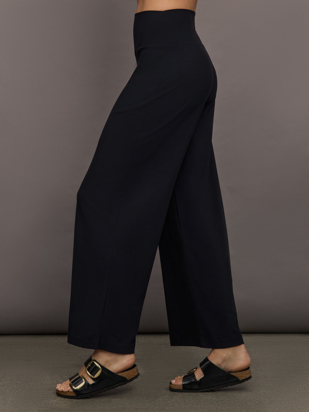 Model is wearing Pleated Palazzo Pant in Melt Black, side profile view.