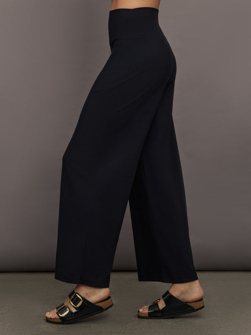 Model is wearing Pleated Palazzo Pant in Melt Black, side profile view.