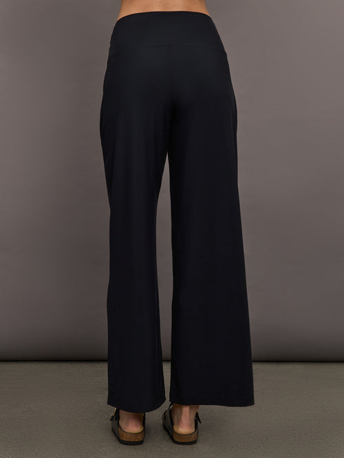 Model is wearing Pleated Palazzo Pant in Melt Black, back view.