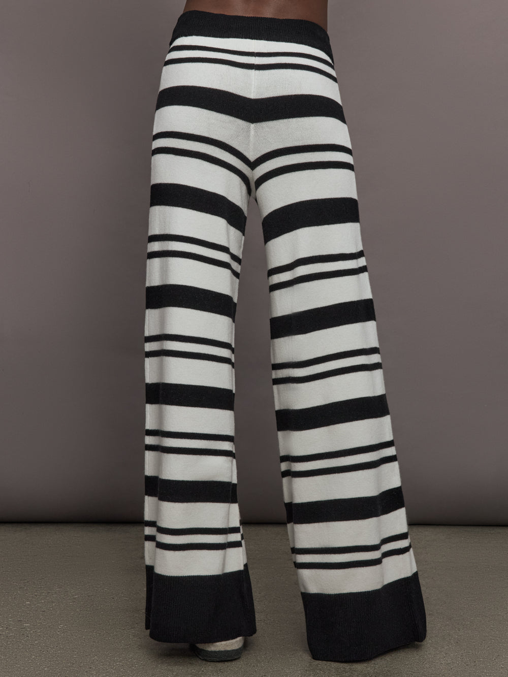 Model is wearing Striped Sweater Pant in black and cream, back view.