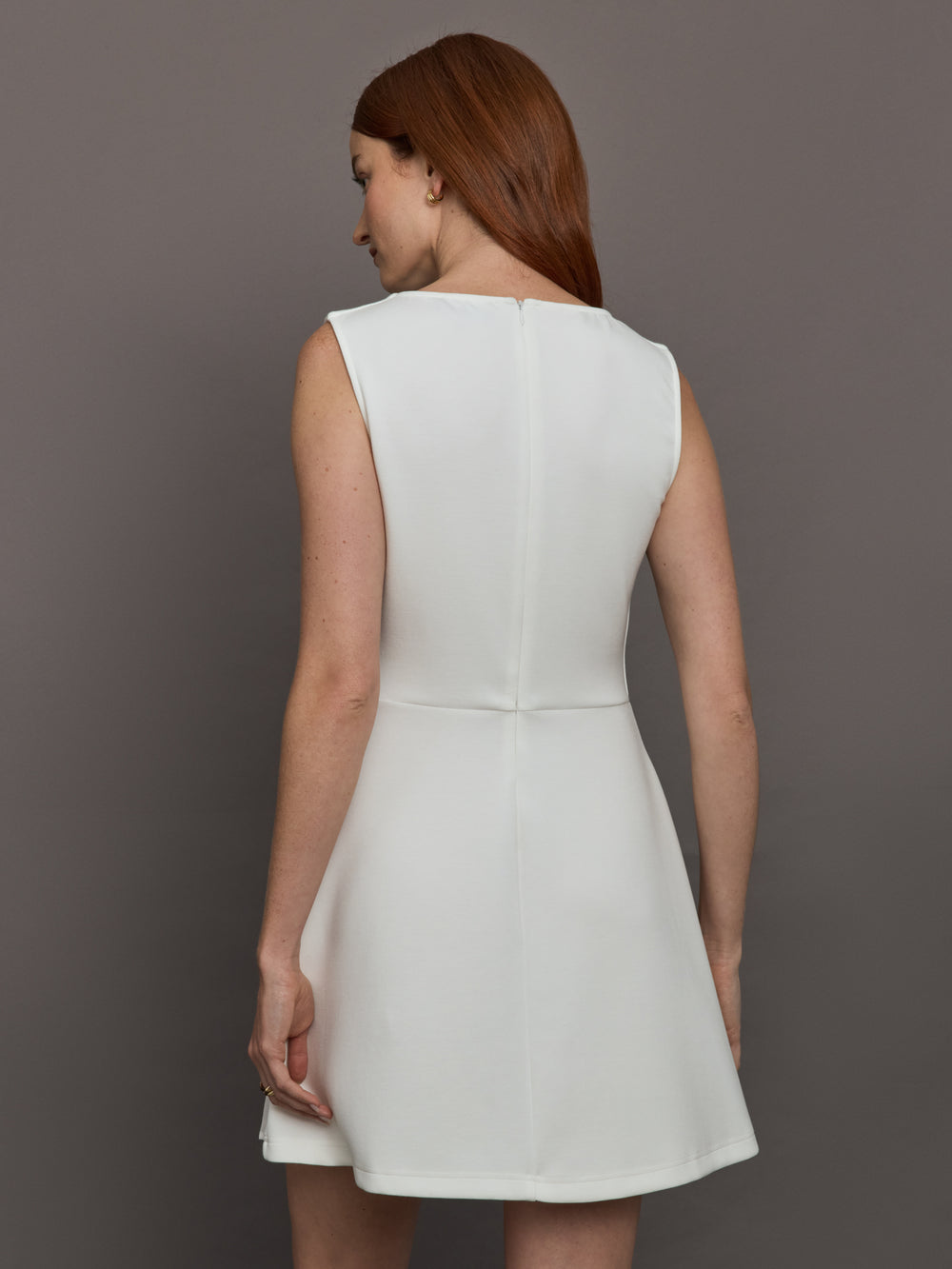 Model wears a white sleeveless tennis dress with pleating below the waist.