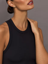 Woman wearing a black ribbed sleeveless dress against a gray background