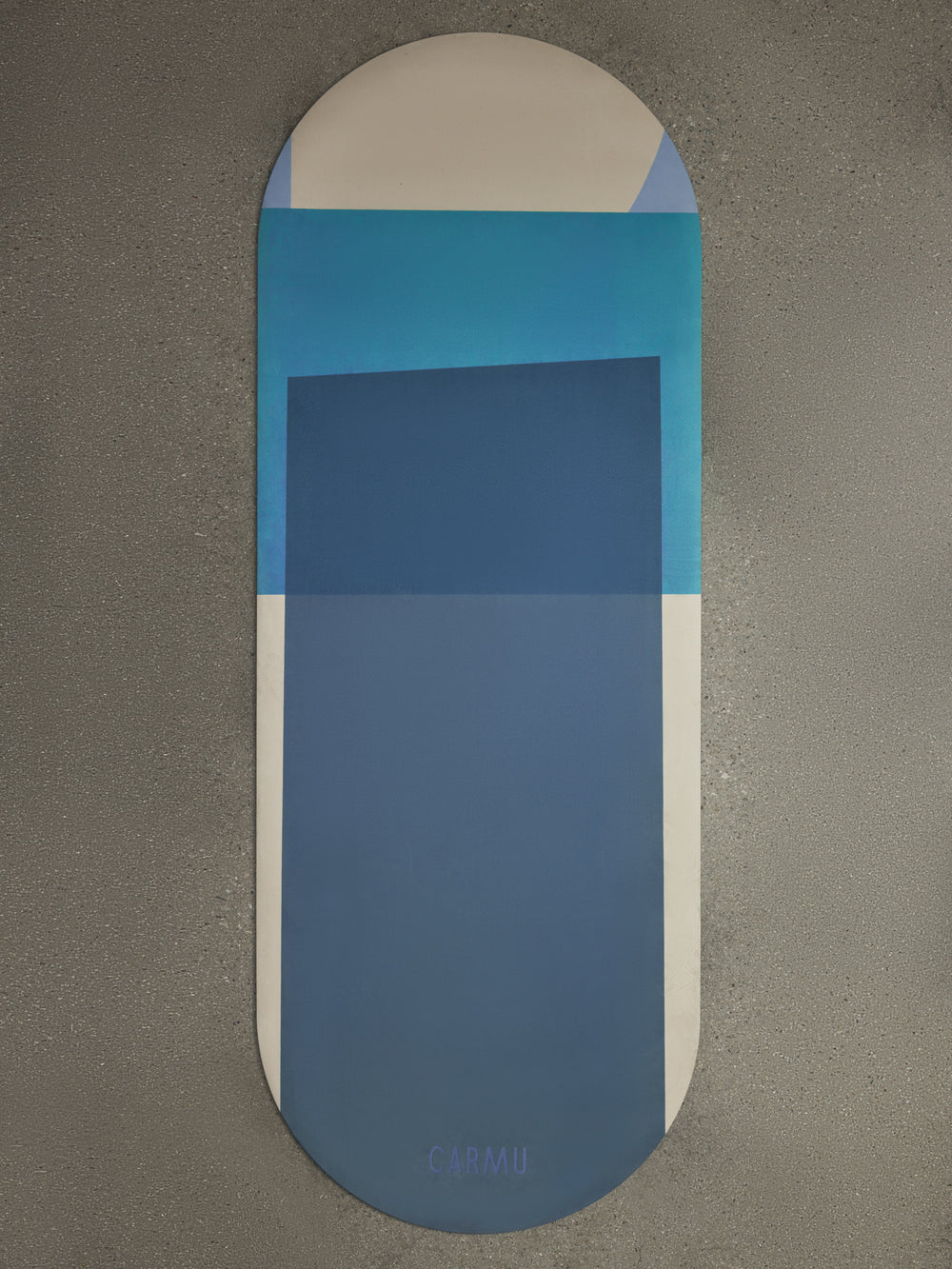 Navy Aeris yoga mat in Navy and Blue geometric design displayed flat on textured concrete surface with CARMU logo.