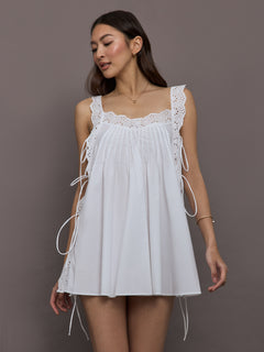 Model is wearing the Lucilla eyelet trimmed open back mini dress in white, full body front view.