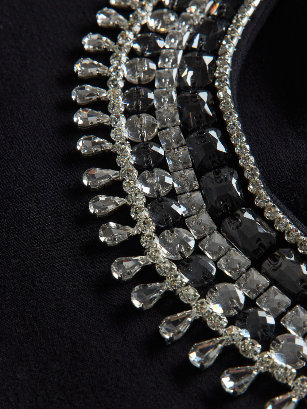 Close-up of black jewel embellished sweatshirt showing crystal beading and textured detail.
