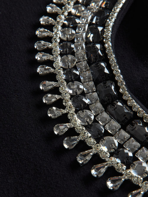 Close-up of black jewel embellished sweatshirt showing crystal beading and textured detail.