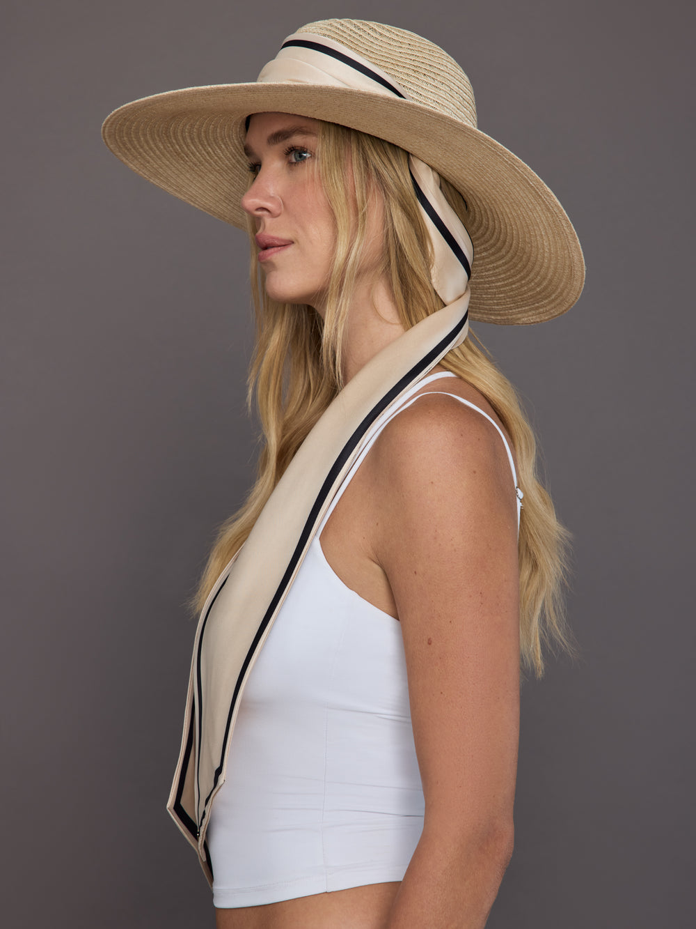 Side profile of model in natural hemp fedora with ivory scarf and contrast trim.