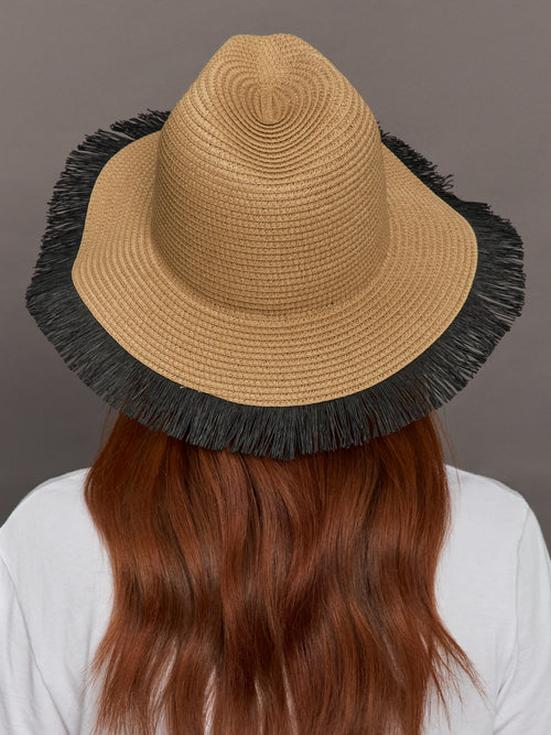  Model wears a caramel-colored straw fedora with a fringed black edge.