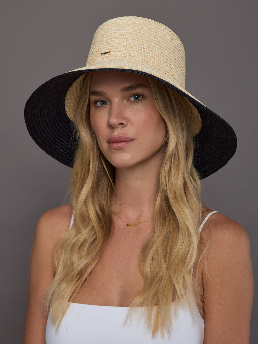 Model wearing ivory wide-brim straw sun hat with black brim, front view.