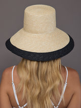 Back view of ivory straw sun hat with wide black brim.