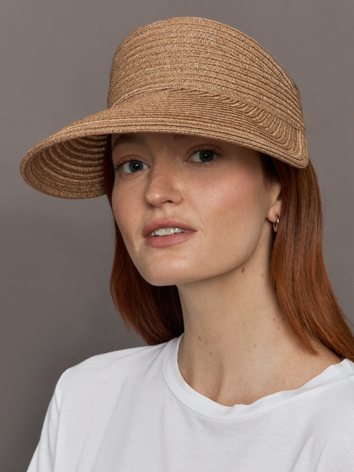 Model wears fawn-colored visor with a wide brim and an ivory ribbon tied at the back.
