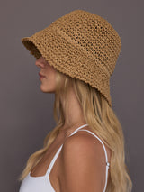 Model is wearing the crochet bucket hat in camel, side view showing brim angle.