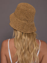 Model is wearing the crochet bucket hat in camel, back view.