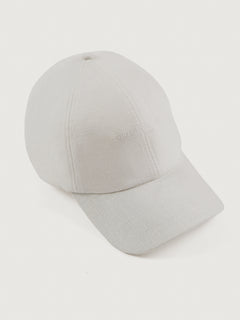 White linen baseball cap with an embroidered logo on the front and a ruched elastic back.