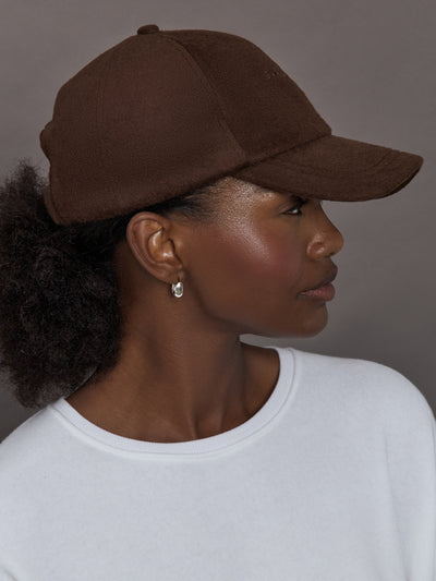 Model wearing a brown cap against a gray background