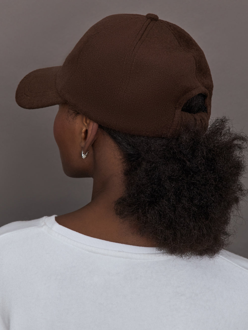Model wearing a brown cap against a gray background