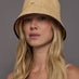 Front view of model wearing natural woven straw bucket hat with dark contrast trim.