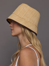 Side profile of model in tan woven straw bucket hat with structured brim.