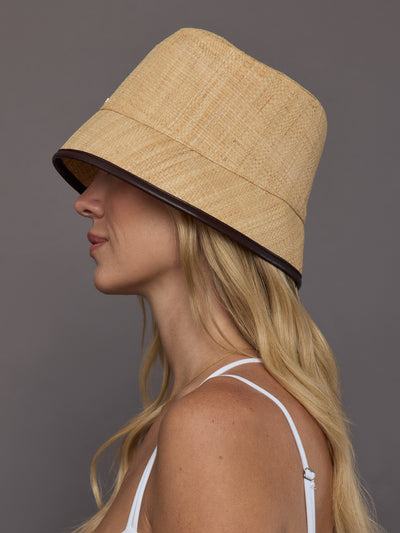 Side profile of model in tan woven straw bucket hat with structured brim.